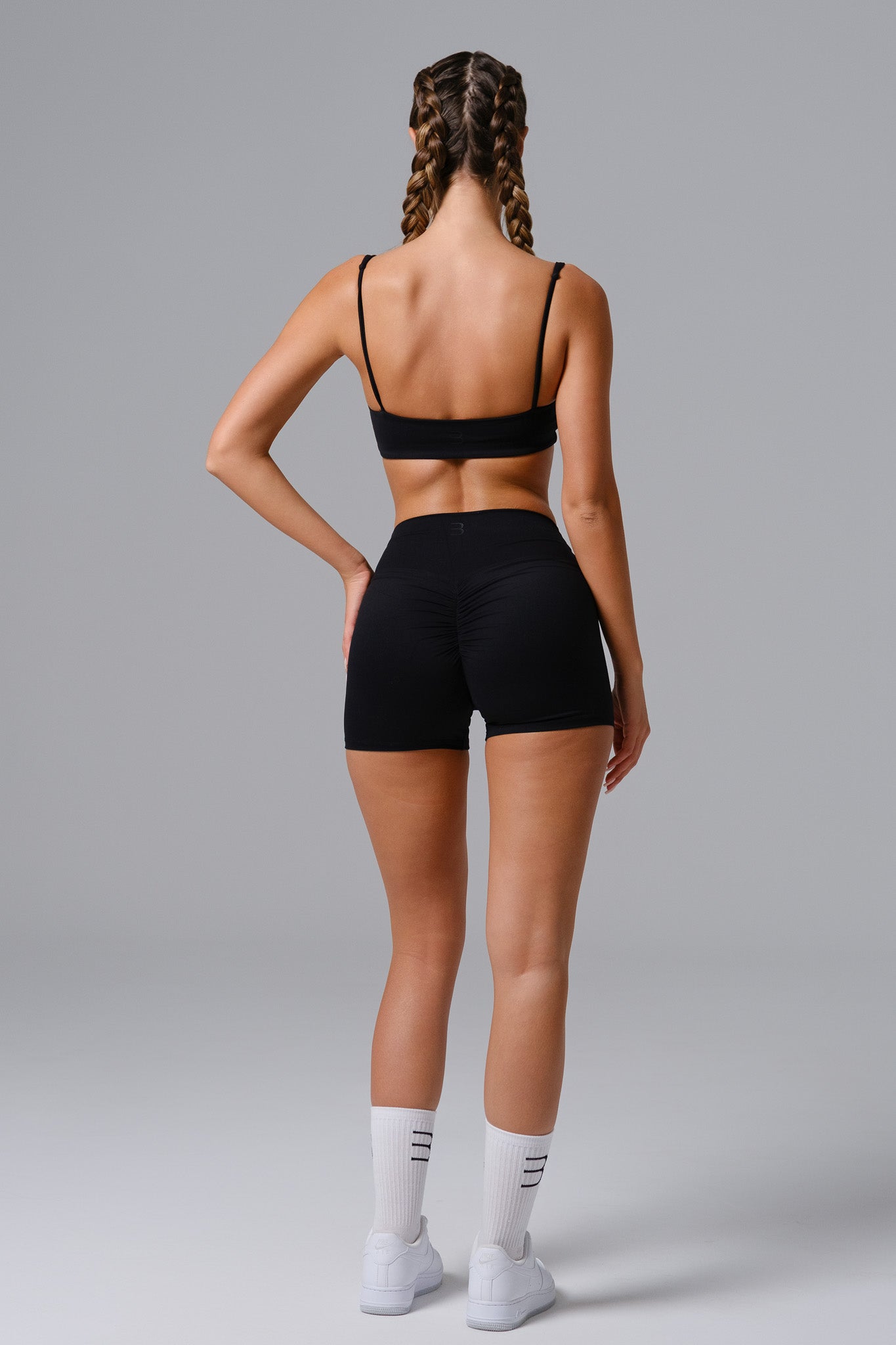 Person wearing a black sports bra and shorts on a gray background