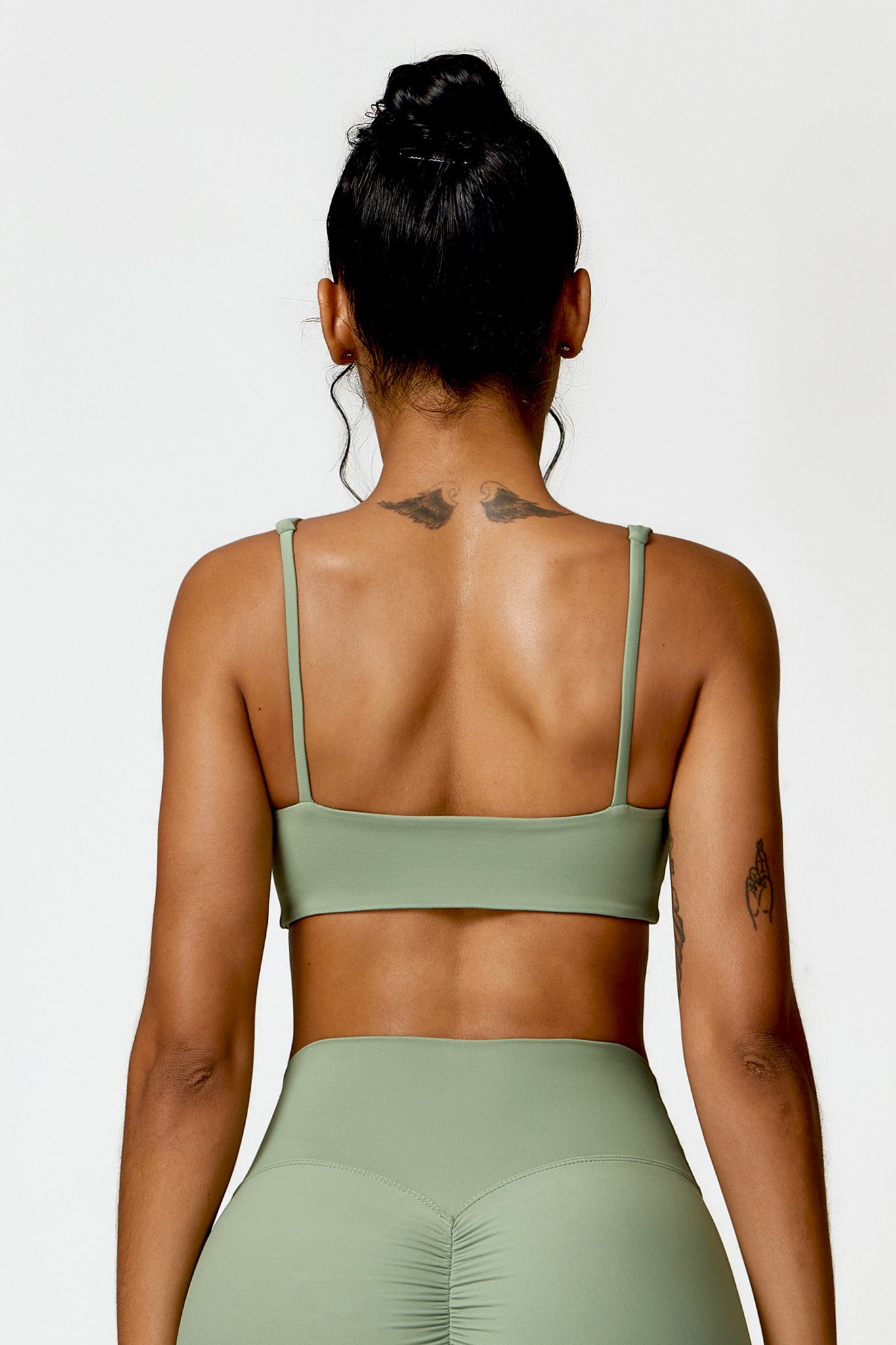 Person wearing a green sports bra and leggings set on a white background