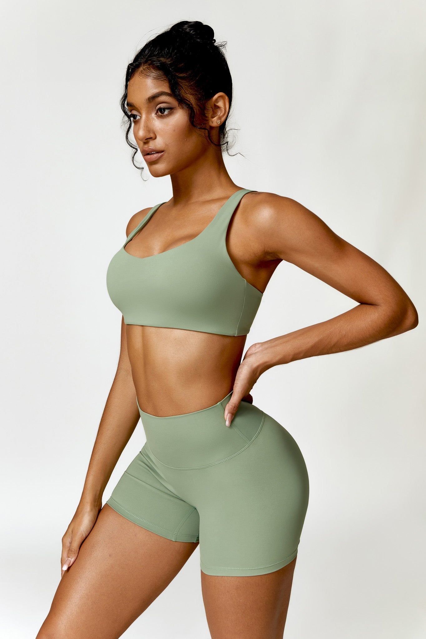Woman wearing a green sports bra and shorts set on a white background