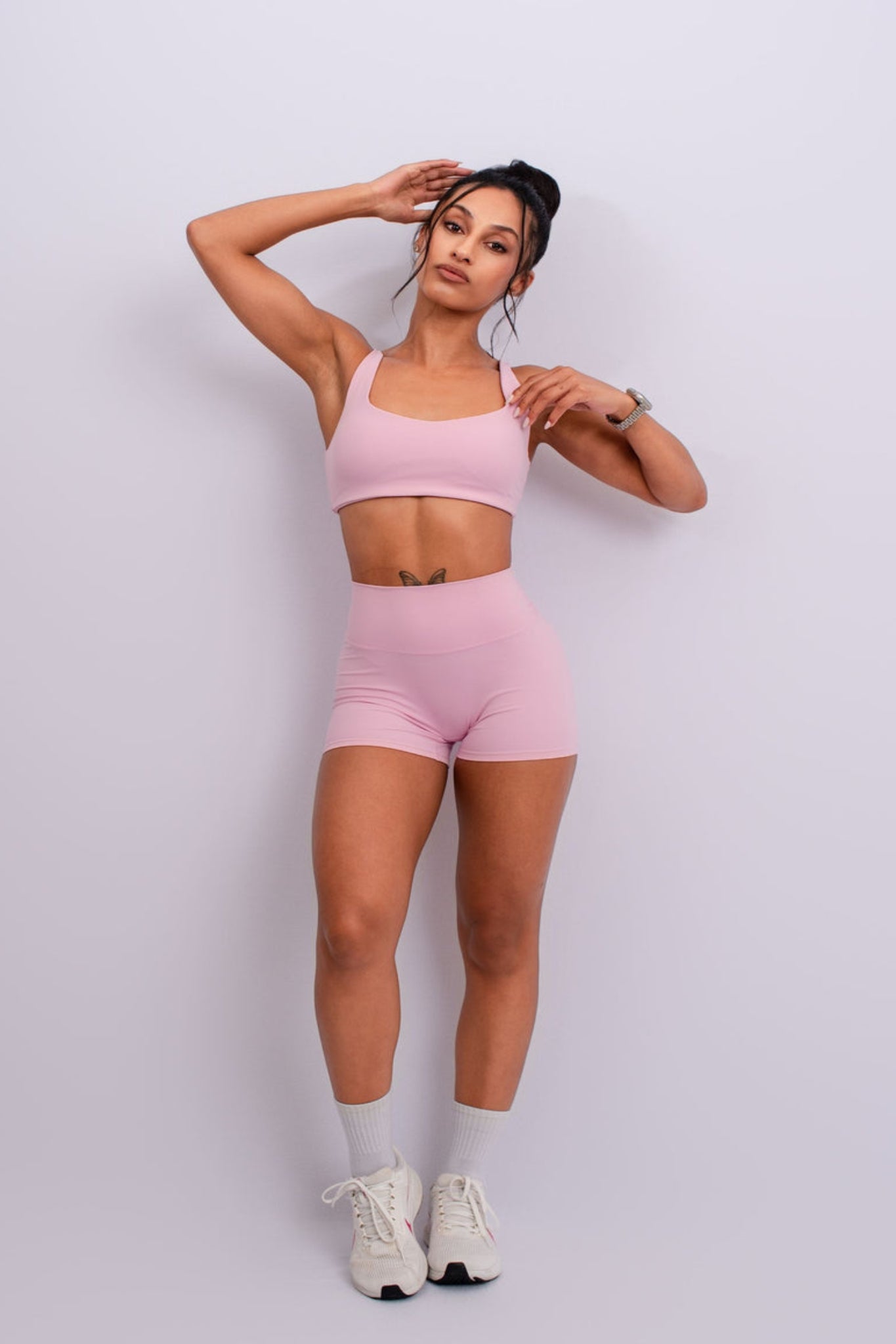 Woman wearing a pink athletic outfit on a light gray background