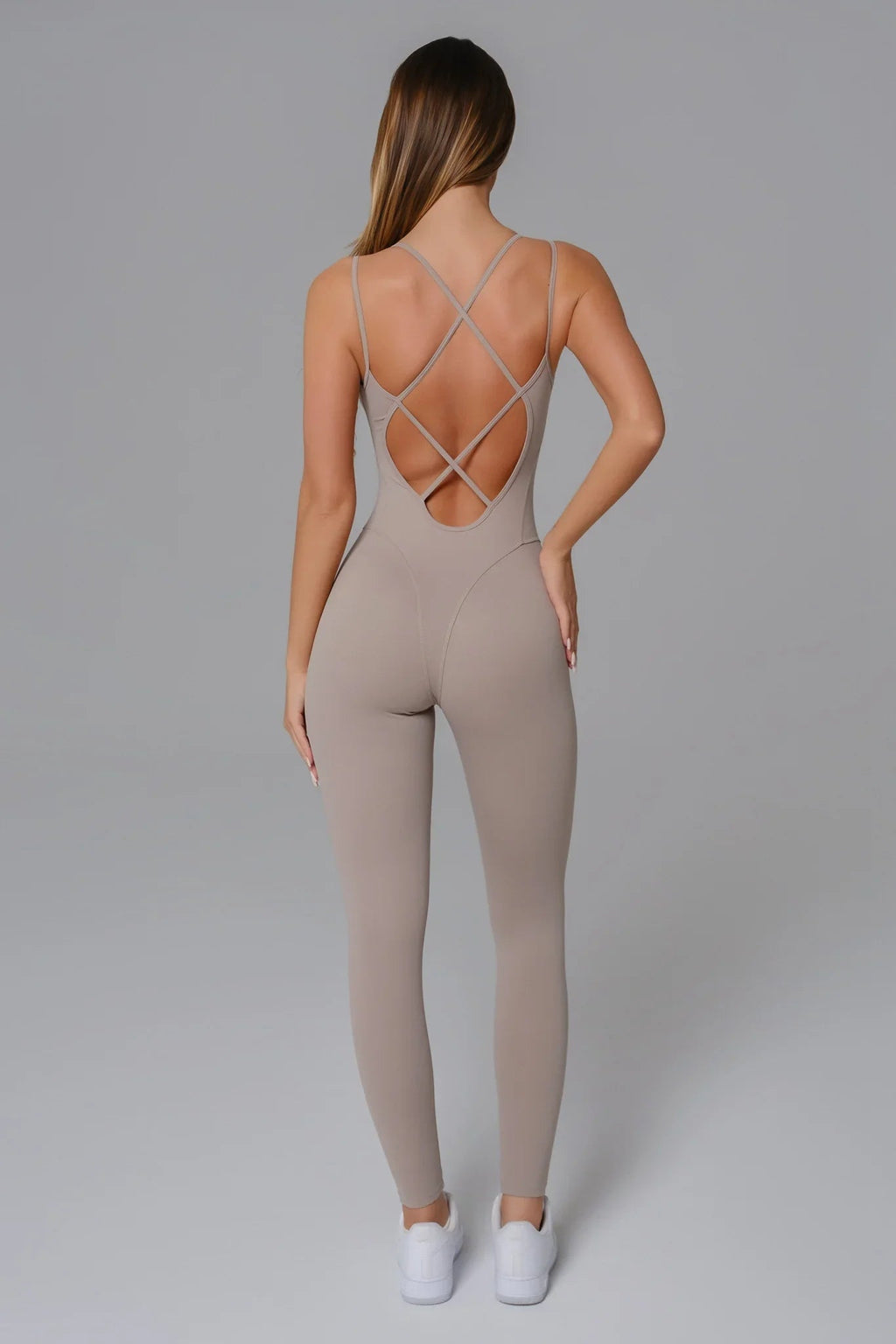 Beige jumpsuit with criss-cross back design on a plain background