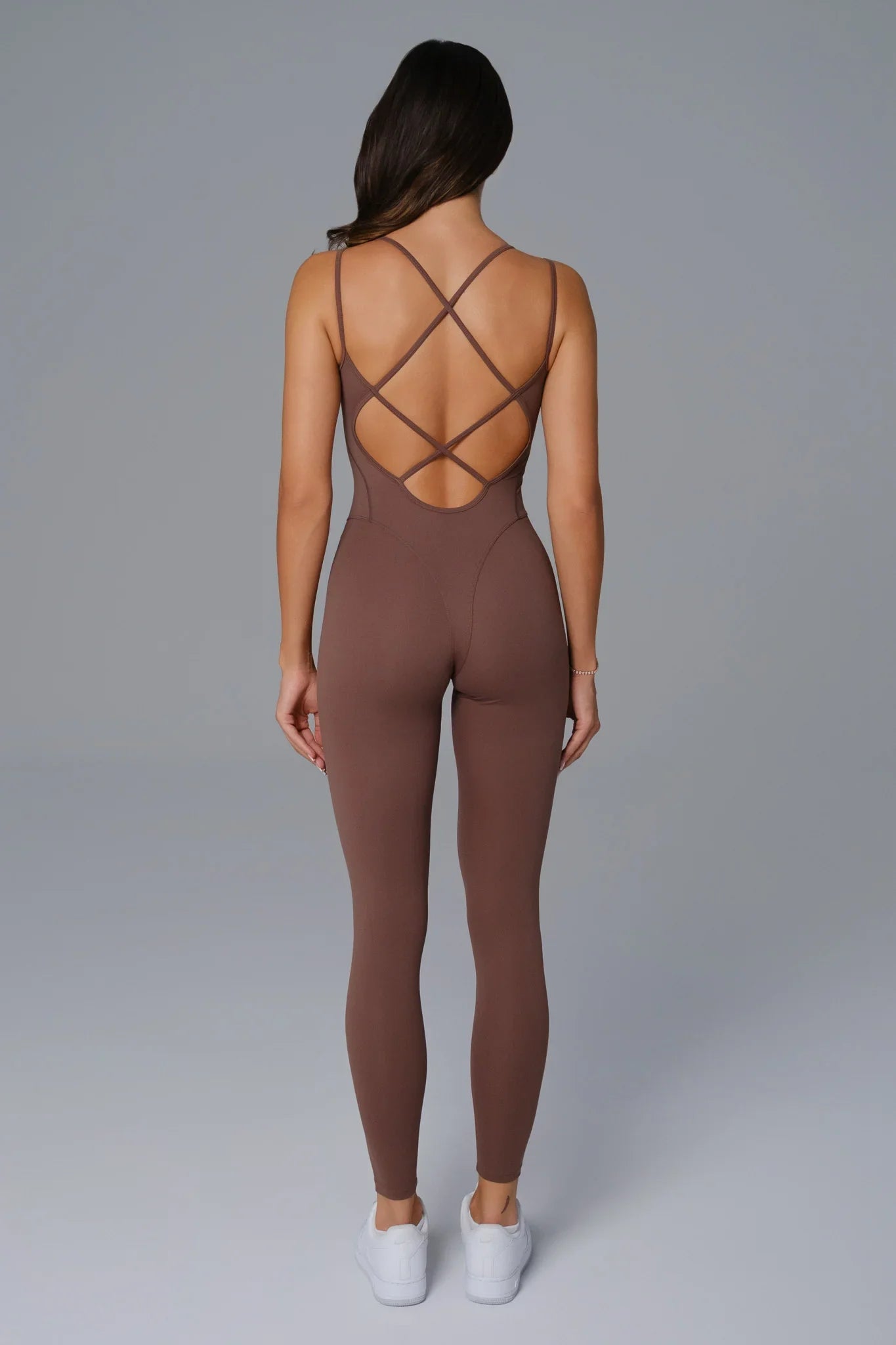 Brown jumpsuit with criss-cross back design on a plain background