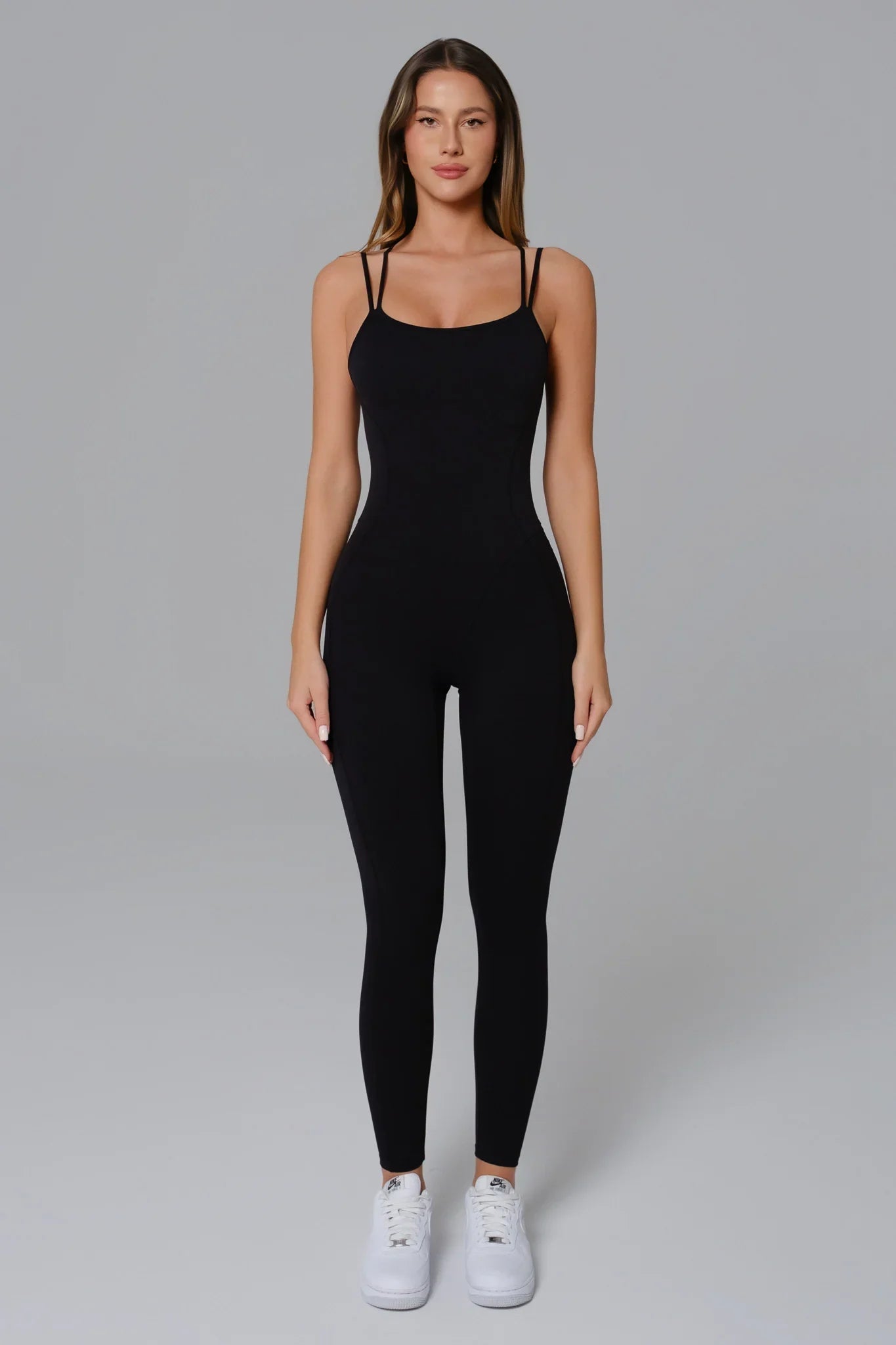 Woman wearing a black jumpsuit on a gray background