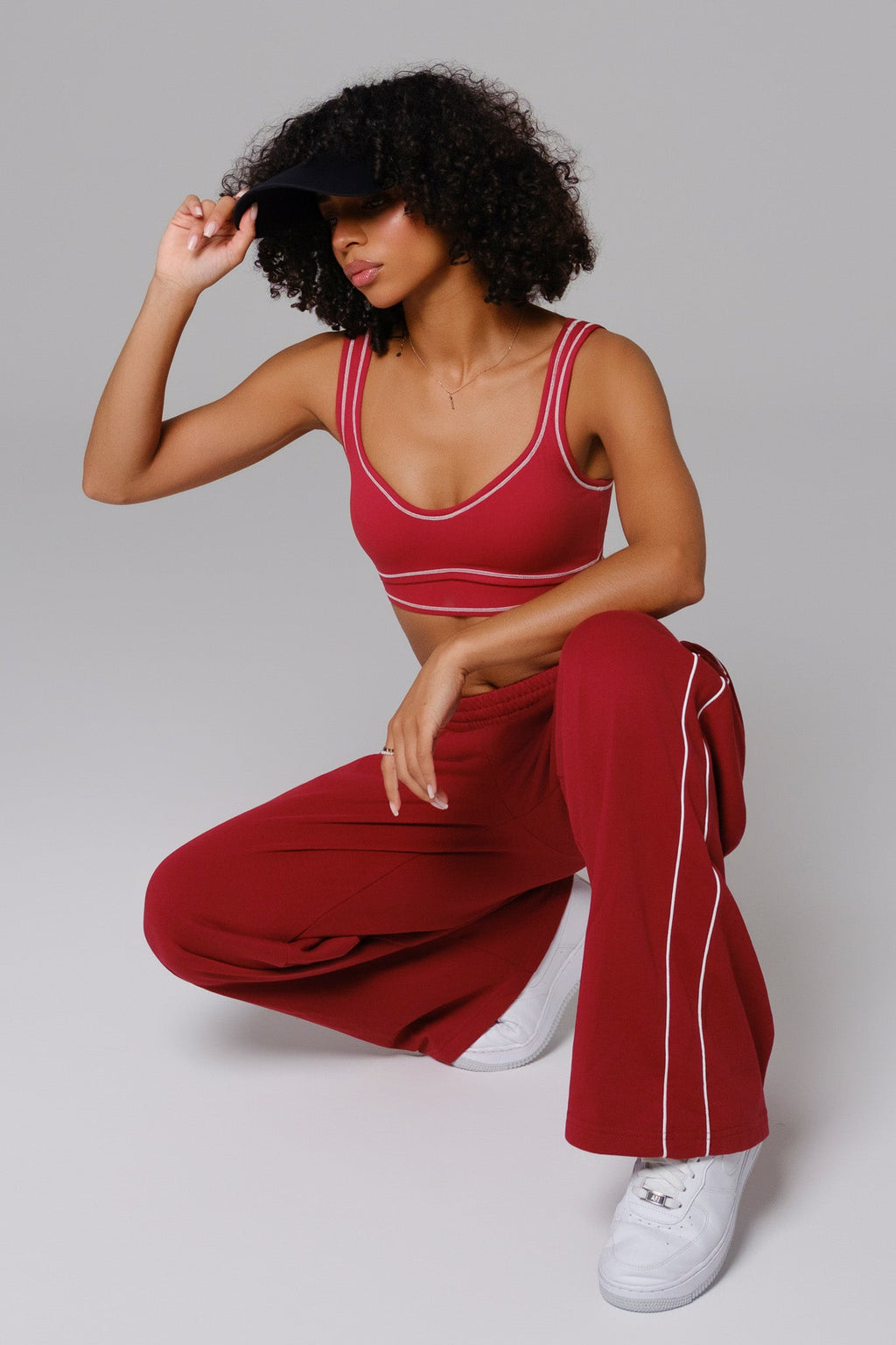 Woman wearing a cherry red sports bra and pants with white piping 