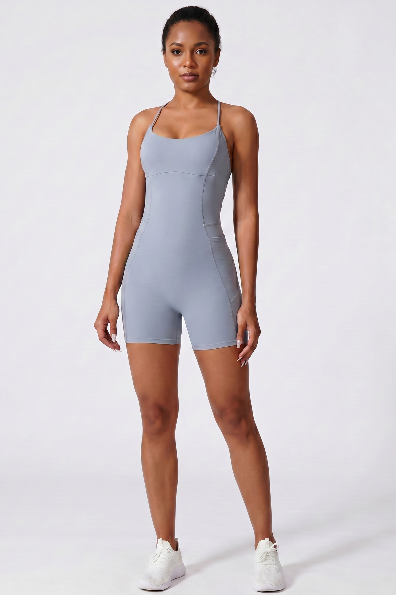 Woman wearing a haze blue bodysuit on a white background