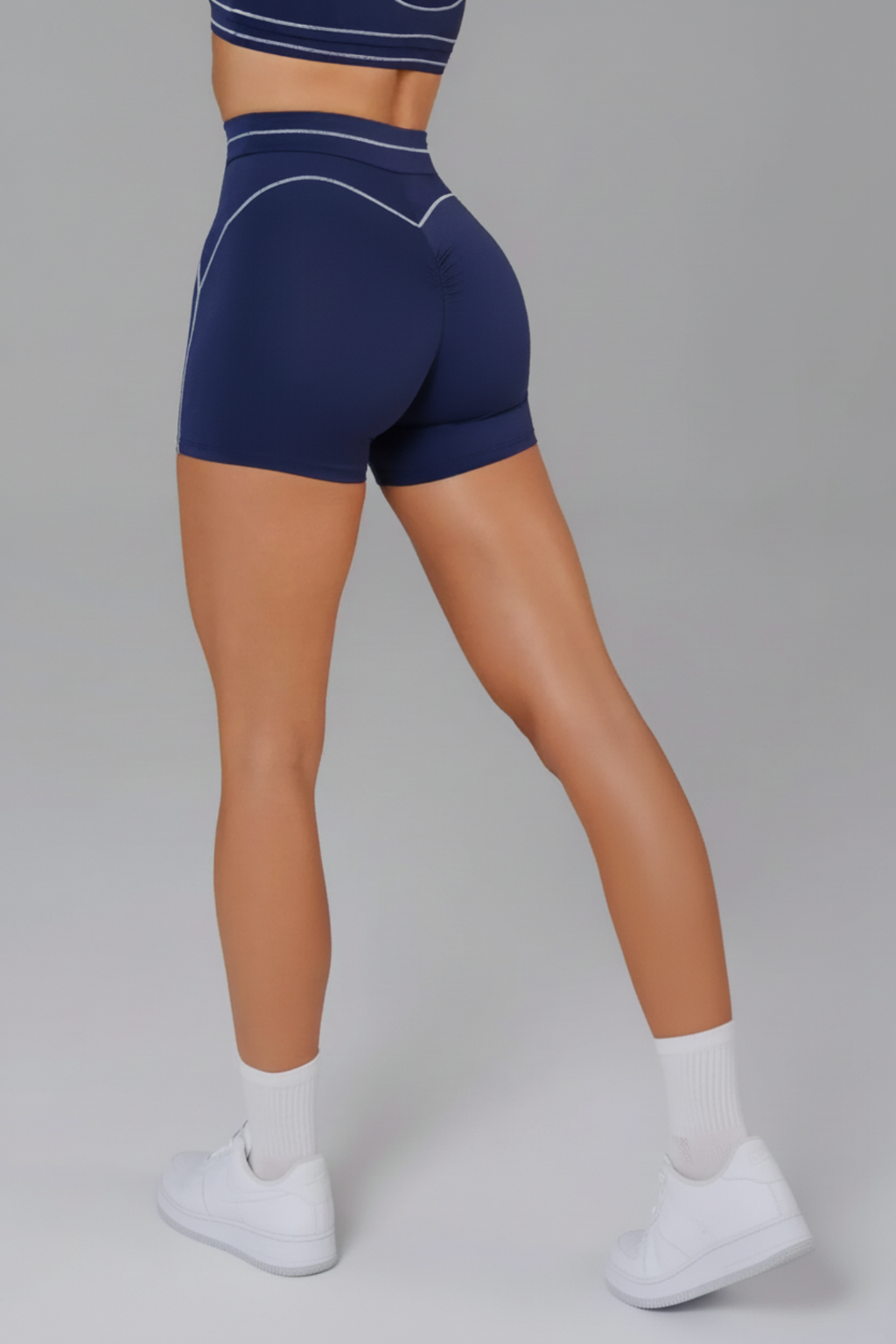 Woman wearing navy blue athletic shorts on a gray background