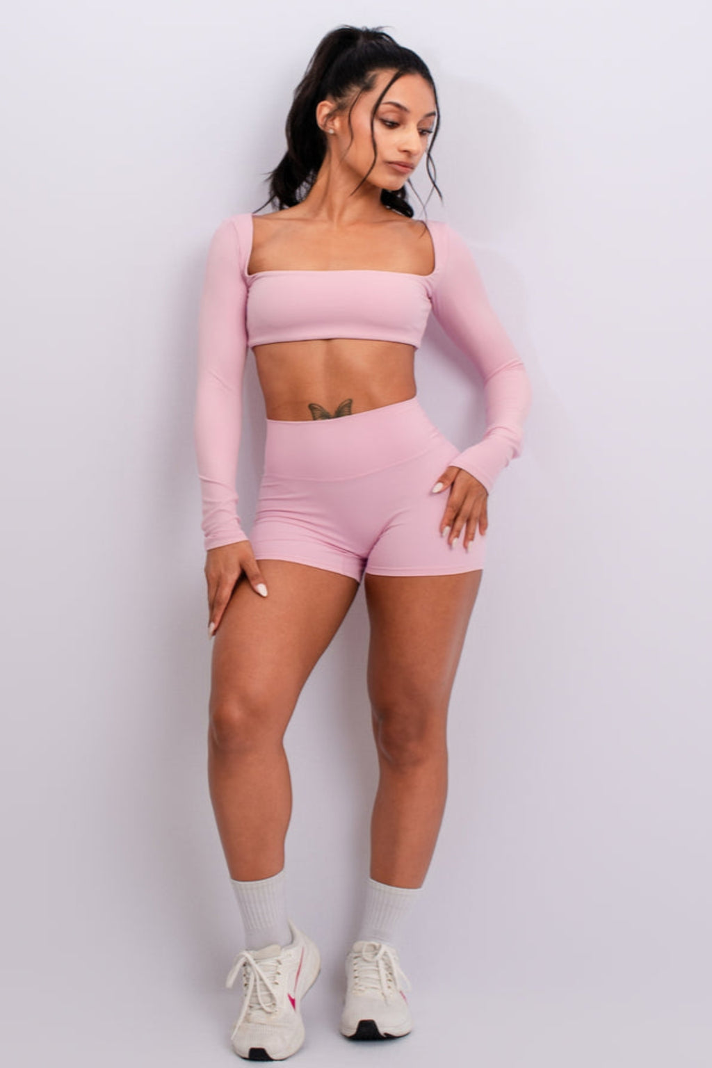 Woman wearing a pink athletic outfit on a light gray background