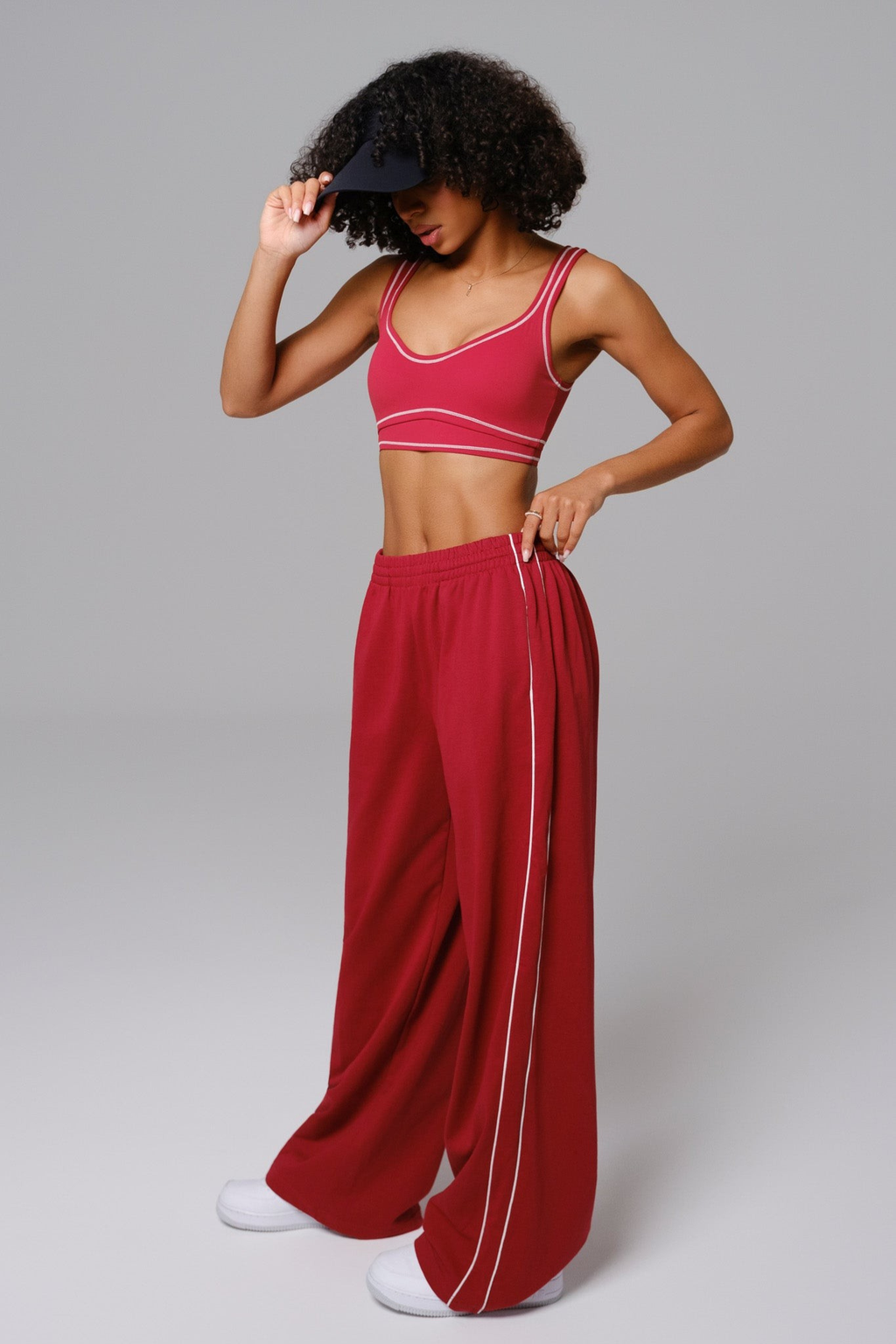 Woman wearing a cherry red sports bra and wide-leg sweatpants 