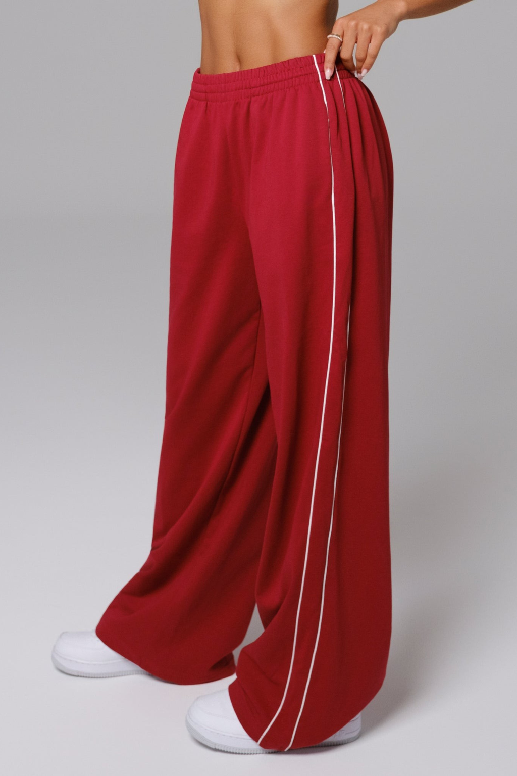 Red track pants with a white stripe on a gray background
