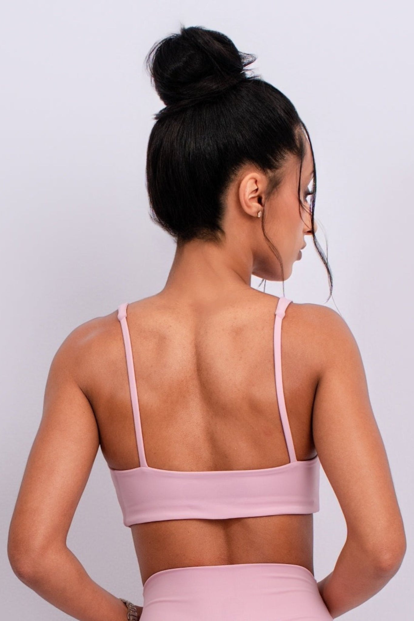 Woman wearing a pink sports bra and leggings against a white background
