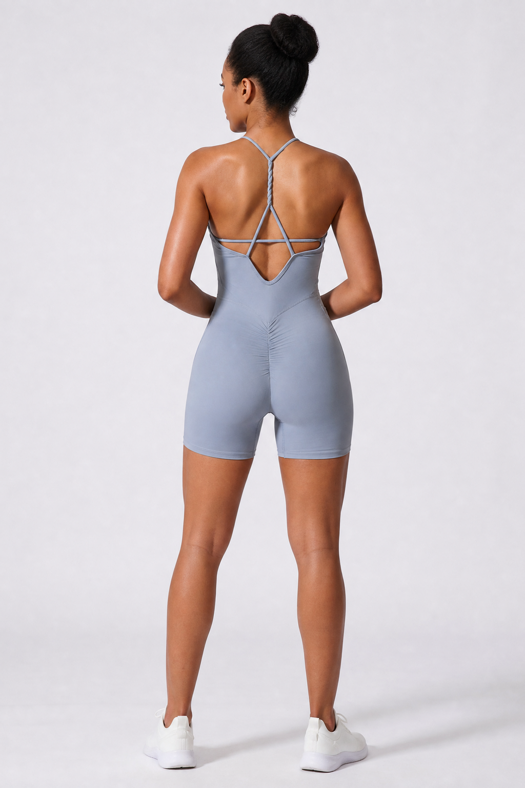 Person wearing a haze blue bodysuit with thin straps on a white background