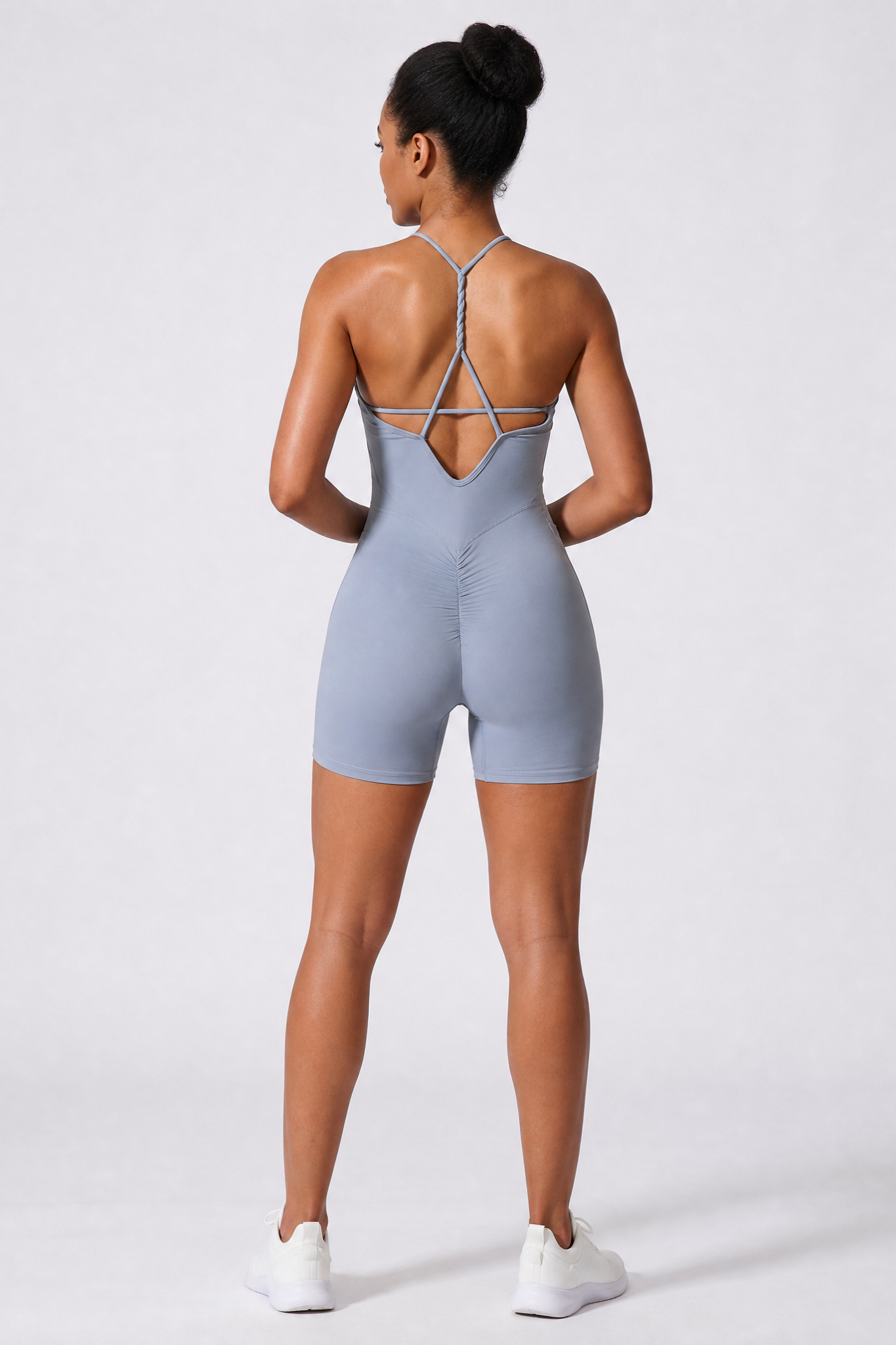 Person wearing a haze blue bodysuit with thin straps on a white background