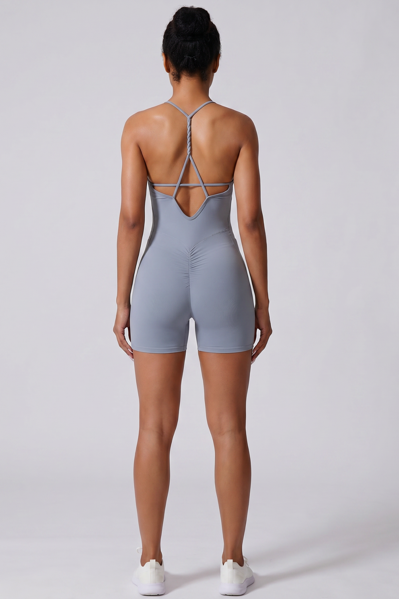 Person wearing a haze blue bodysuit with thin straps on a white background