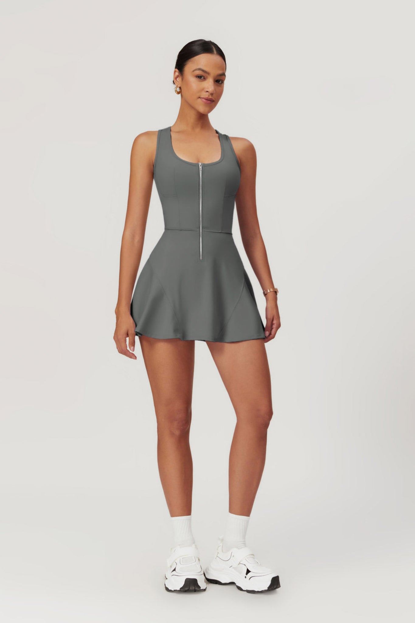 Woman wearing a gray tennis dress on a white background